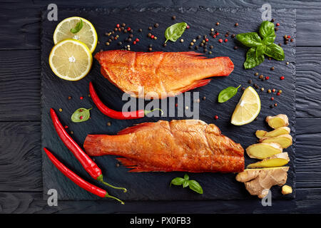 Vue aérienne de vivaneaux rouge fumé à chaud sur une plaque en pierre noire avec des épices, des herbes et des tranches de citrons, vue de dessus, flatlay Banque D'Images