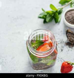 Vue du dessus de l'eau dans la région de chia pot Mason avec fraise et menthe sur fond de ciment gris. Chia infusé avec de l'eau detox de baies. L'espace de copie pour le texte. La saine alimentation, boissons, alimentation, concept detox Banque D'Images