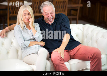 L'homme ayant un bon rire tandis que sa femme pleure Banque D'Images