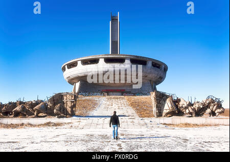 Vue arrière de l'homme à marcher en direction de capacités dans un communiste abandonné Buzludzha, monument à la montagnes des Balkans de la Bulgarie. Banque D'Images