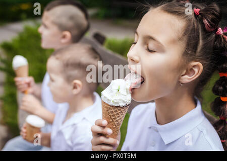 Beaux enfants adorables eating ice cream assis sur un banc en bois dans le parc concept de vacances fun. Banque D'Images