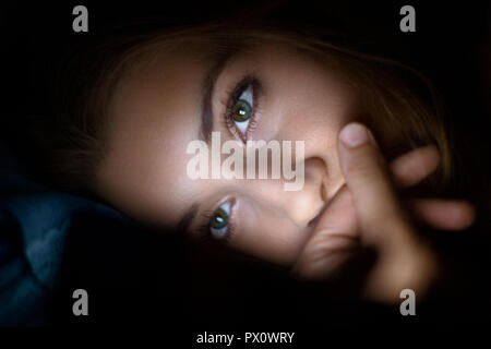 Girl in bed with smartphone la lecture des messages Banque D'Images