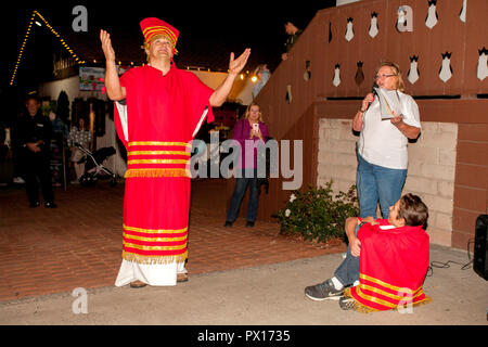 Un bénévole local reenacts l'histoire de Saint Martin qui donne la moitié de son manteau à un mendiant alors qu'un narrateur explique l'histoire à un festival de Noël à Huntington Beach, CA. Banque D'Images