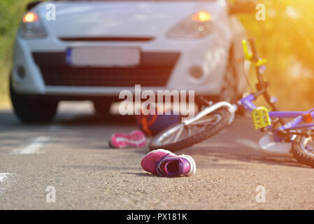 Close-up of a kid chaussure tombée sur l'asphalte à côté d'un vélo après accident de voiture sur la rue de la ville Banque D'Images