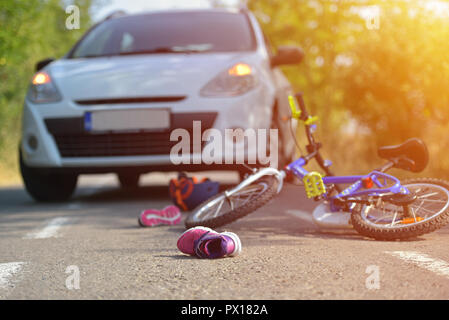 Close-up of a kid chaussure tombée sur l'asphalte à côté d'un vélo après accident de voiture sur la rue de la ville Banque D'Images