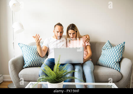 Portrait d'un jeune homme avec sa petite amie sur ordinateur portable à la maison piscine Banque D'Images