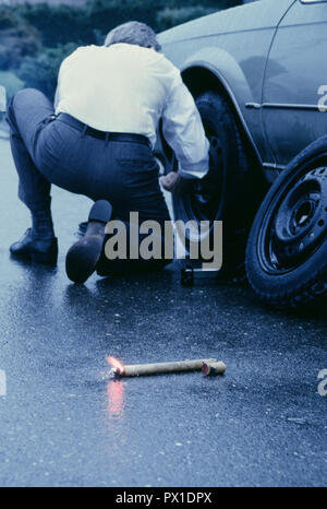 Businessman changer un pneu à plat sous la pluie, USA Banque D'Images