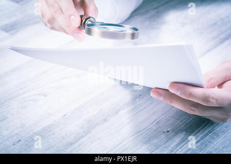 Businessman Reading ses documents à l'aide d'une loupe Banque D'Images