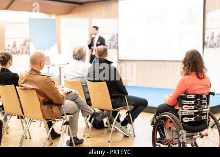 Vue arrière du nrecognizable femme sur un fauteuil roulant qui participent à des discours de conférence. Banque D'Images