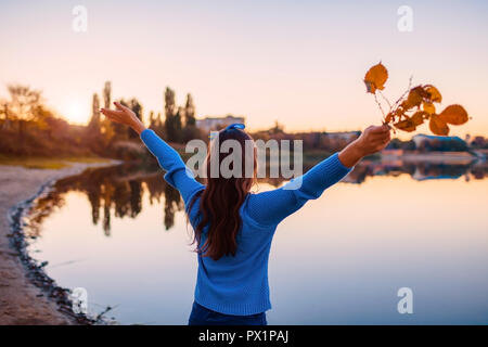 Jeune femme admirant automne rivière scène avec relevé et ouvert mains tenant des branches. De Presse et de l'énergie libre Banque D'Images