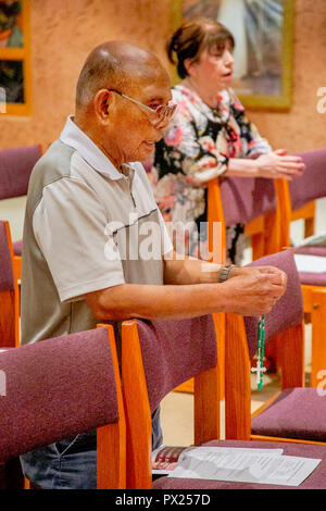 Un vieil homme vietnamien est titulaire d'un chapelet qu'il s'agenouille en prière pendant la messe dans une Laguna Niguel, CA, l'église catholique. Banque D'Images