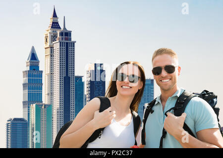 Portrait Of A Smiling Young Couple Wearing Sunglasses In City Banque D'Images