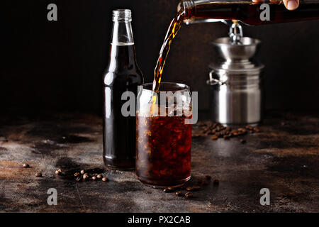 Cold brew café glacé dans des bouteilles en verre est versé sur la glace Banque D'Images