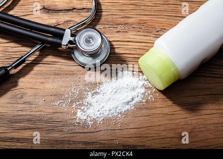 Close-up du produit répandu de la poudre de talc et stéthoscope sur fond de bois Banque D'Images