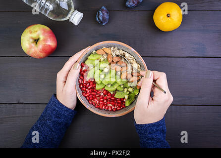 Vue du dessus montrant les mains bien manger l'avoine avec kiwi et d'amande sur une table en bois. Concept de remise en forme et d'un style de vie sain. Vue d'en haut Banque D'Images