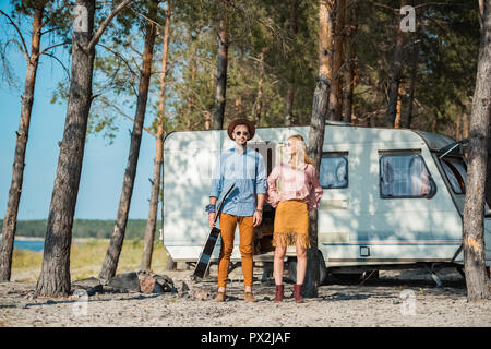 Jeune couple hippie avec guitare acoustique posant près de campervan Banque D'Images