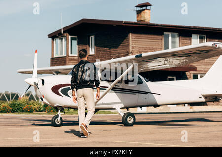 Vue arrière de l'élégant male pilot in airplane veste en cuir autour de Banque D'Images
