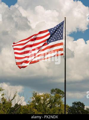 Le soleil ne frappe un United States drapeau américain qu'il vagues dans le vent contre un ciel partiellement nuageux Banque D'Images