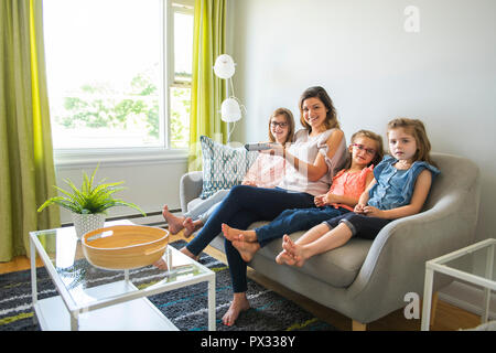 La mère et les filles sur le canapé à la maison écouter plat Banque D'Images