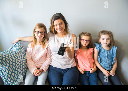 La mère et les filles sur le canapé à la maison écouter plat Banque D'Images