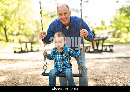 Un grand-père en poussant son petit-fils sur la corde swing Banque D'Images