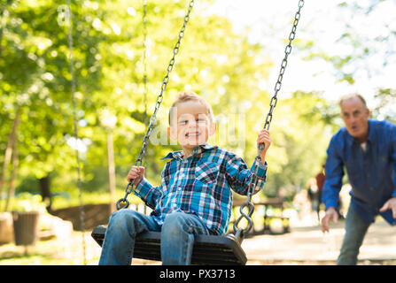 Un grand-père en poussant son petit-fils sur la corde swing Banque D'Images