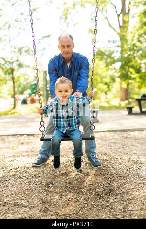 Un grand-père en poussant son petit-fils sur la corde swing Banque D'Images