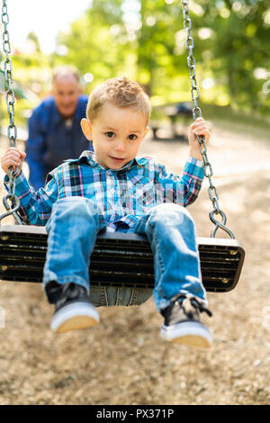 Un grand-père en poussant son petit-fils sur la corde swing Banque D'Images