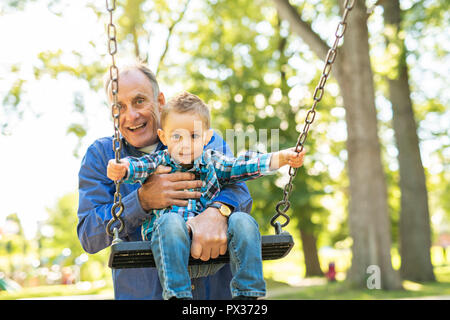 Un grand-père en poussant son petit-fils sur la corde swing Banque D'Images