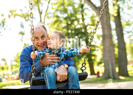 Un grand-père en poussant son petit-fils sur la corde swing Banque D'Images