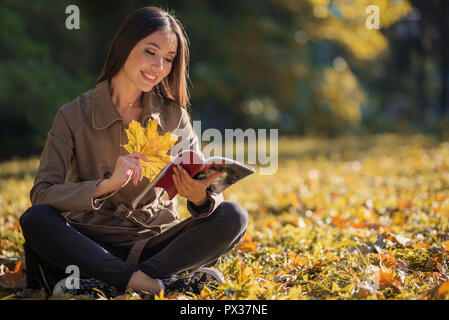 Femme au cours de l'automne, style de concept. Une jeune asiatique est une femme adulte bénéficiant du beau temps au cours de l'automne, dans un parc avec des feuilles jaunes. Banque D'Images