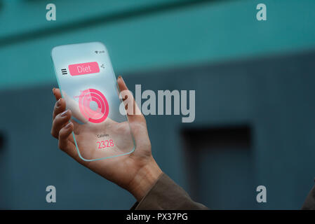 Gros plan sur une femme main qui tient un concept gadget téléphone transparent, à l'aide d'une app sur régimes check up, Banque D'Images