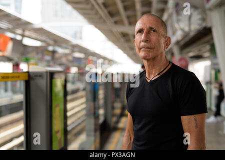 Senior homme chauve touristiques attendent le train à train aérien BTS s Banque D'Images
