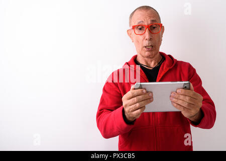 Studio shot of bald man using digital tablet while lookin Banque D'Images