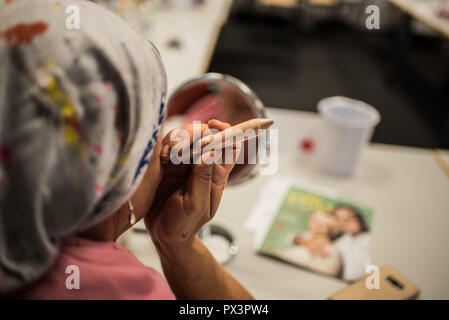 Mainz, Allemagne. 19 Oct, 2018. 19 octobre 2018, l'Allemagne, Mainz : une femme avec le cancer est maintenant un concealer stick dans son maquillage classe. Le traitement du cancer par chimiothérapie ou radiothérapie peut considérablement modifier l'apparence du patient avec la perte de cheveux, perte de cils et sourcils ou l'irritation de la peau. Le fichier de donneurs de moelle osseuse, Allemand (DKMS) propose pour les femmes concernées en particulier sur il a coordonné les cours de mise à niveau. Crédit : Andreas Arnold/dpa/Alamy Live News Banque D'Images