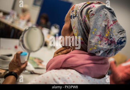 Mainz, Allemagne. 19 Oct, 2018. 19 octobre 2018, l'Allemagne, Mainz : une femme souffrant du cancer met sur un coton dans la classe. Le traitement du cancer par chimiothérapie ou radiothérapie peut considérablement modifier l'apparence du patient avec la perte de cheveux, perte de cils et sourcils ou l'irritation de la peau. Le fichier de donneurs de moelle osseuse, Allemand (DKMS) propose pour les femmes concernées en particulier sur il a coordonné les cours de mise à niveau. Crédit : Andreas Arnold/dpa/Alamy Live News Banque D'Images