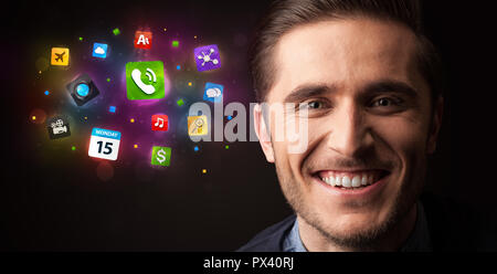 Portrait of a young businessman with applications colorées à côté de lui sur un fond sombre Banque D'Images