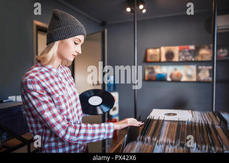 Belle jeune femme parcourt les enregistrements dans le magasin de disques vinyle Banque D'Images