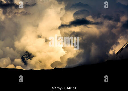 Silhouette spectaculaire de collines contre un ciel orageux rempli de nuages au crépuscule avec un jeu de lumière et d'ombres. Banque D'Images