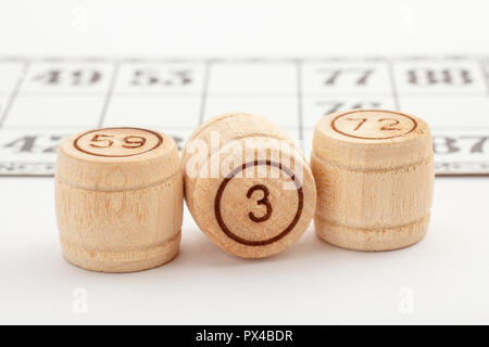 Tonneau en bois et trois numéros de carte pour un jeu de loto sur un fond blanc. Vue rapprochée Banque D'Images