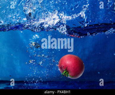 Tomber dans l'eau de tomate avec splash Banque D'Images