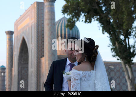 Une Bride and Groom posing lors d'une séance de photographie de mariage à la place publique de Registan, qui fut le coeur de la ville antique de Samarkand de la dynastie timouride dans la ville de Samarkand alternativement Samarqand en Ouzbékistan Banque D'Images