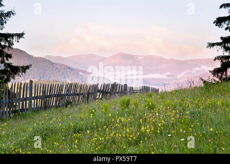 Prairie de montagne avec une clôture en bois, vue sur les montagnes, tôt le matin Banque D'Images