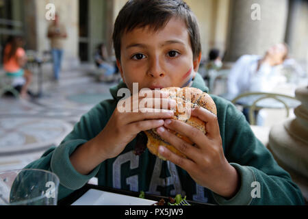 11-year-old boy eating a hamburger à Paris, France. Banque D'Images