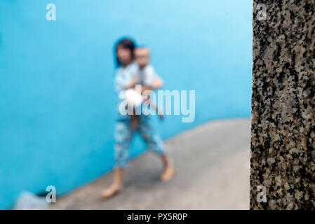 Fille qui marche sur une petite rue contre un mur bleu. Homme marchant sur une petite rue contre un mur bleu. Ho Chi Minh Ville. Le Vietnam. Banque D'Images