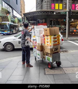 L'homme tirant un chariot chargé avec les boîtes de carton de fruits dans Pitt Street Sydney NSW Australie. Banque D'Images