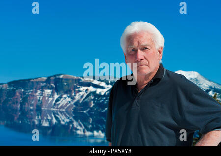 Un bel homme âgé examine l'appareil photo avec le lac du cratère dans l'arrière-plan Banque D'Images