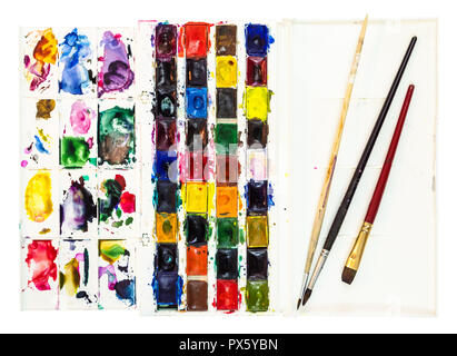 Ensemble de peintures aquarelle utilisé dans un coffret plastique avec palette et pinceaux peu dans le couvercle isolé sur fond blanc Banque D'Images