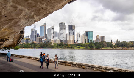 Les piétons marchant sur le long chemin Farm Cove Le Port de Sydney avec les immeubles de bureaux et de la CDB sur l'horizon un jour nuageux Sydney NSW Australie. Banque D'Images