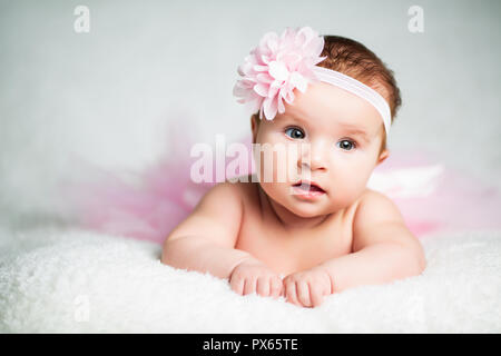 Magnifique petite fille dans des draps blancs à la maison l'air agréable Banque D'Images